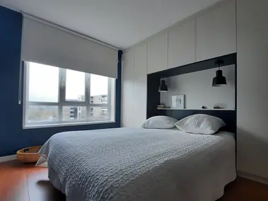 Peinture murale bleu marine et store enrouleur blanc dans une chambre au parquet.