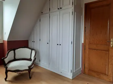 Armoires blanches moulurées sous pente avec peinture deux tons et parquet clair.