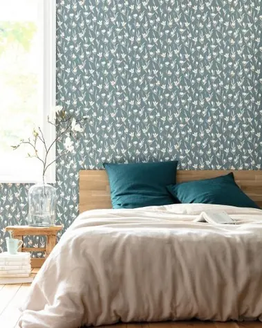 Chambre avec papier peint bleu motif oiseaux, lit en bois clair et coussins bleu canard.