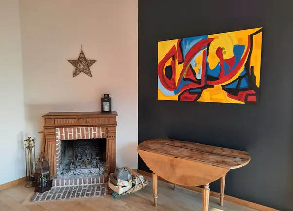 Peinture intérieure mur gris anthracite et rose pâle, cheminée en bois et parquet.