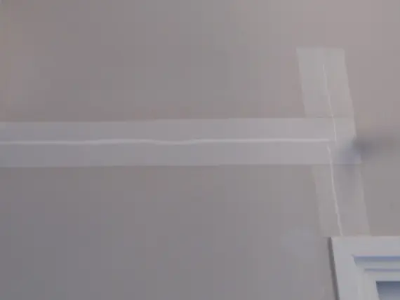 Préparation d'un angle mural avec scotch de masquage pour peinture.